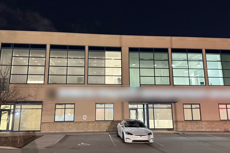 The office building on Bristol Circle at night: two storeys of cut stone and tall gridded windows, lit from inside, over a parking court